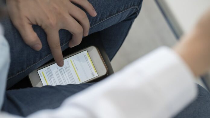 Crop view of student scrolling smartphone trying to copy an exam